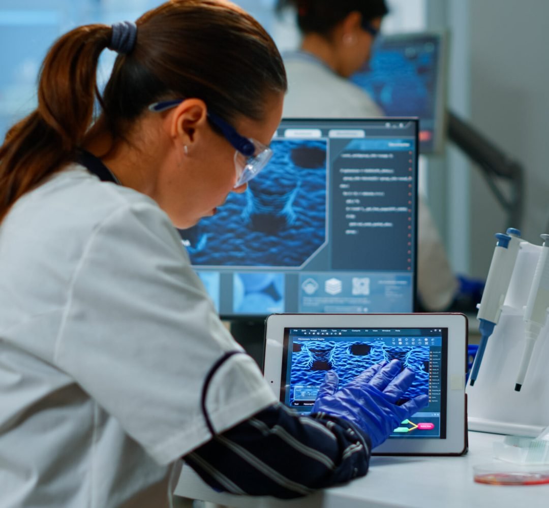 Scientist using digital tablet working in modern medical research laboratory, analyzing DNA information. Medicine, biotechnology research in advanced pharma lab, examining virus evolution